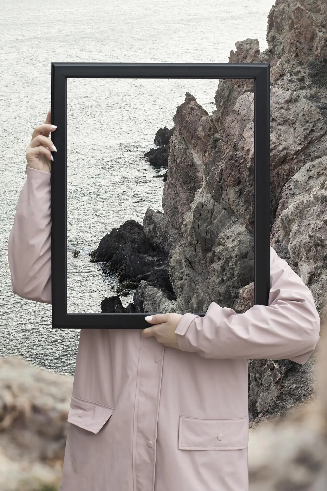 Person hält einen Rahmen mit dem Konzept einer offenen Naturlandschaft.